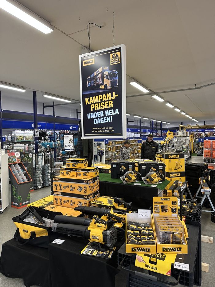 Digital skärm med verktygskampanj ovanför en produktdisplay i en butik