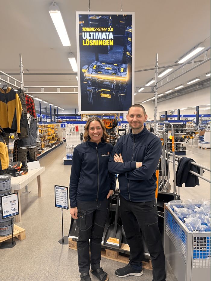 Butikspersonal framför en digital kampanjskärm