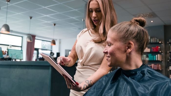 Frisör och kund tittar tillsammans på en surfplatta
